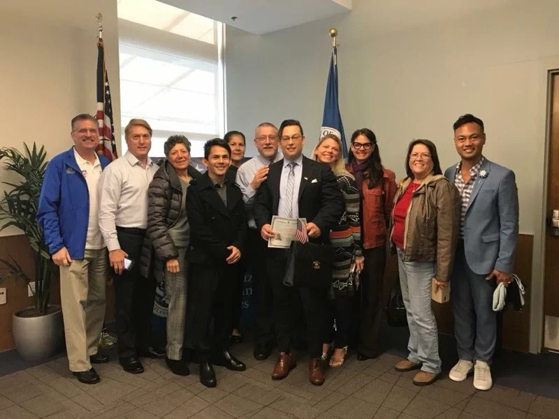 Group celebrates in office with certificates, flag, and awards.