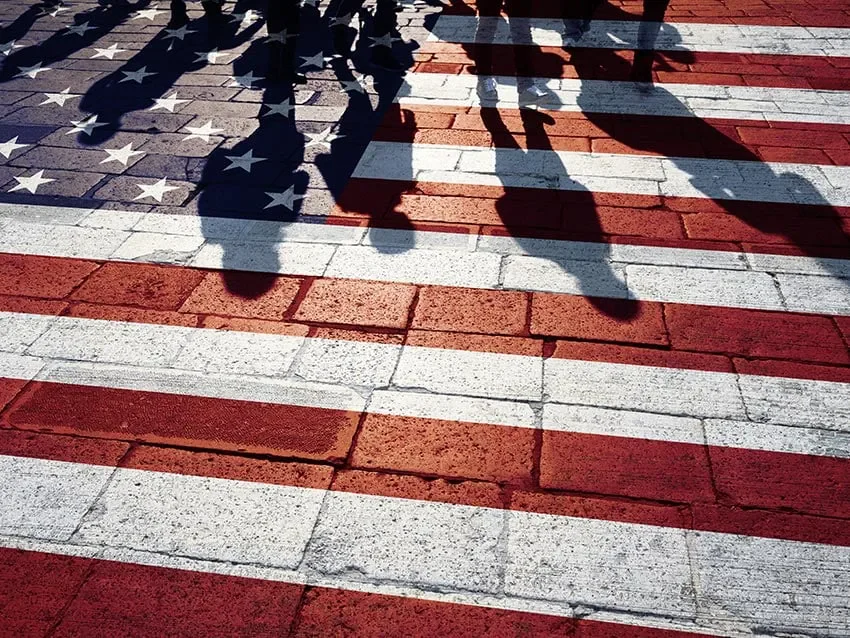Silhouetted pedestrians on pavement styled like the American flag.
